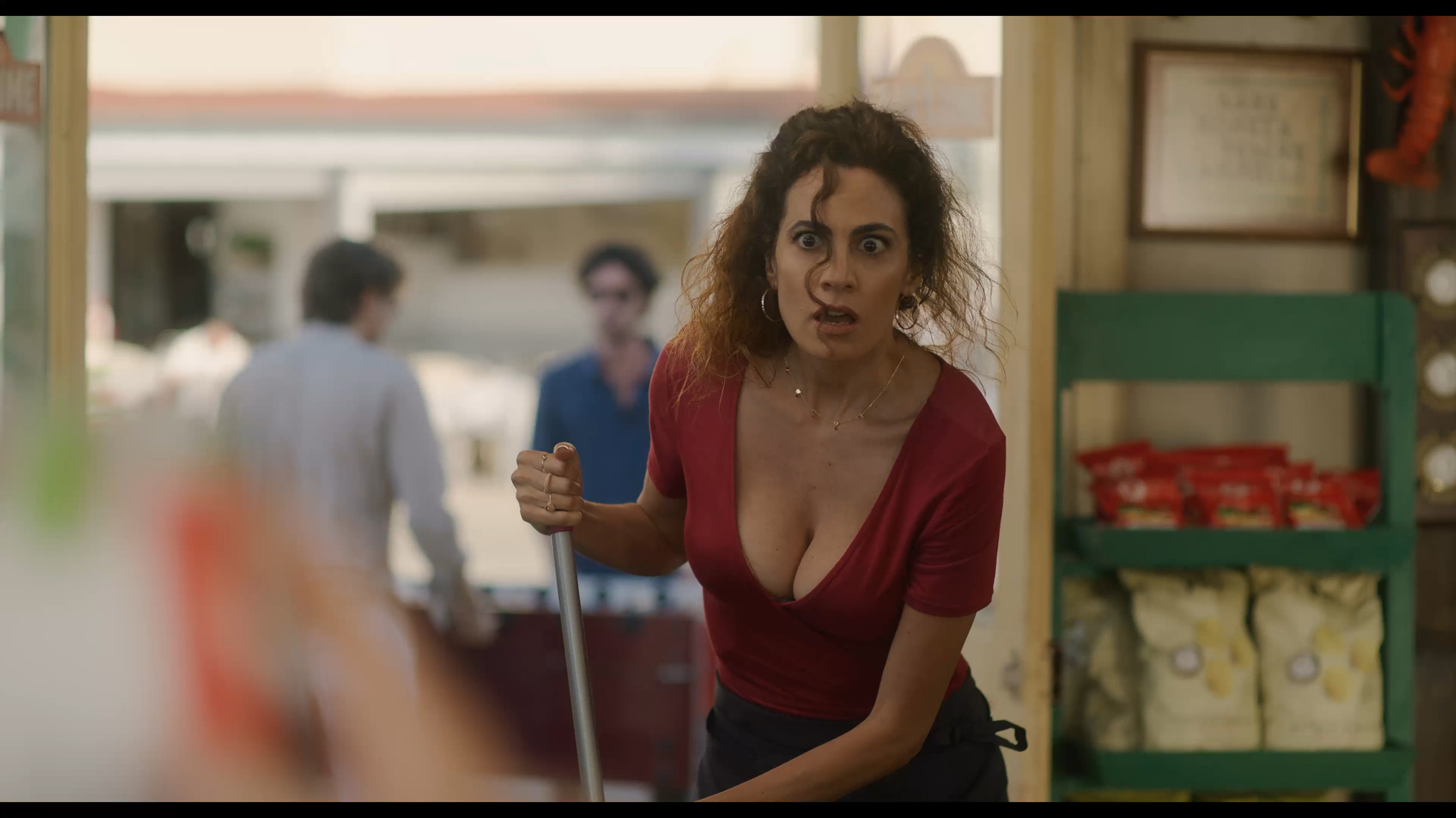 Donna in maglia rossa con la scopa in negozio