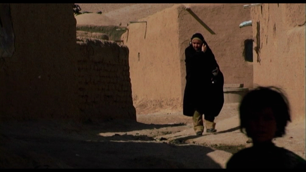 Donna con le cuffie fra le case di terra
