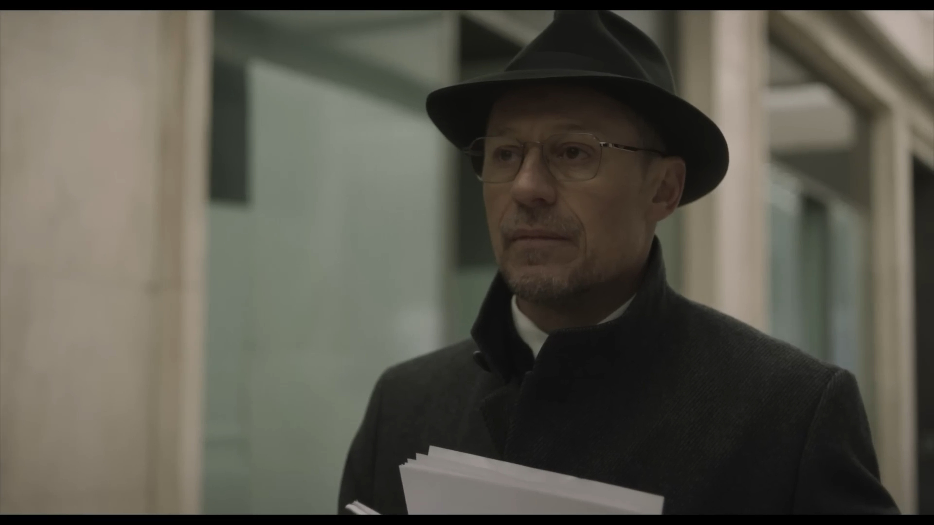 Uomo con cappello e cappotto, documenti in mano