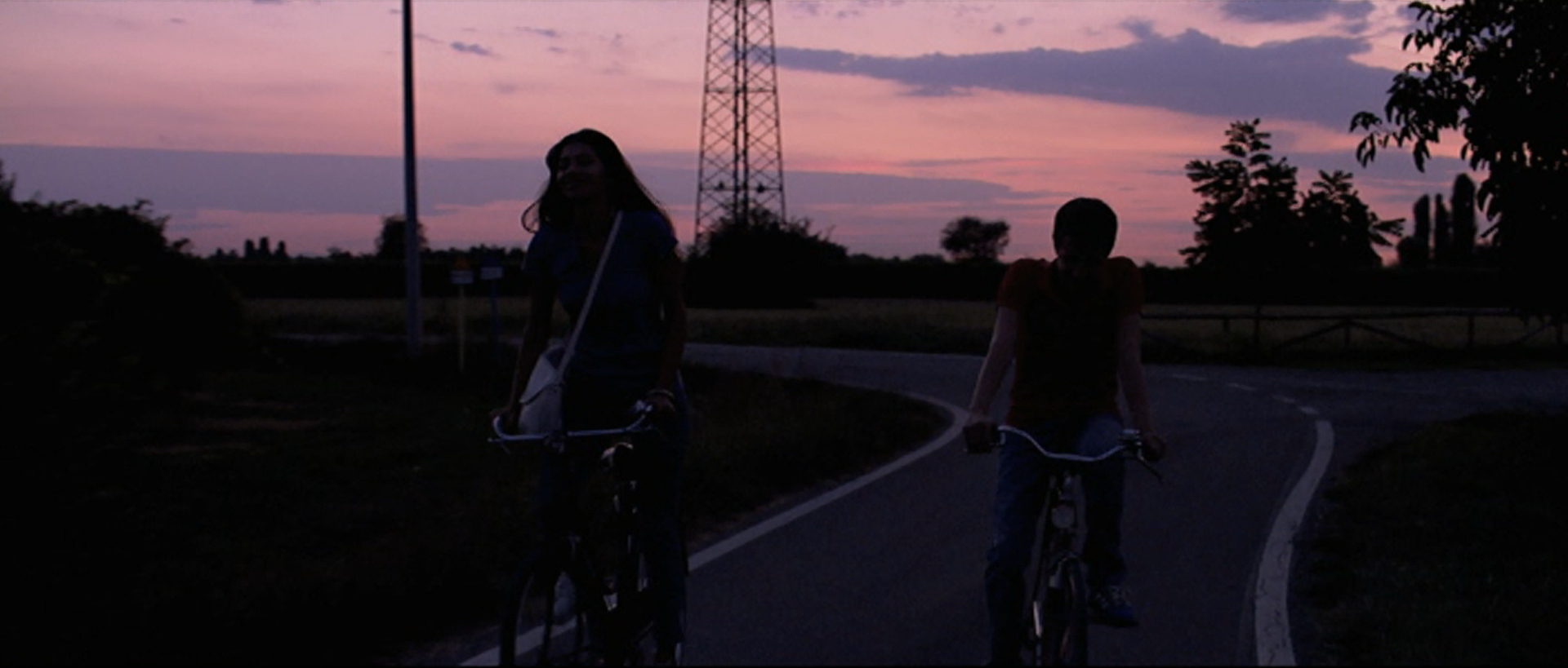 Due ragazzi in bicicletta al tramonto